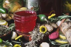 a jar filled with red liquid surrounded by herbs