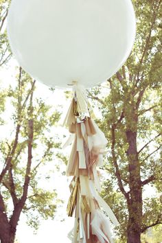 a large white balloon hanging from the side of a tree