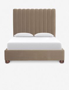 an upholstered bed with white sheets and brown headboard