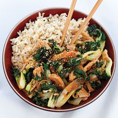 a bowl filled with rice, broccoli and other vegetables next to chopsticks