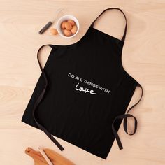 a black apron with the words do all things with love written on it next to eggs and utensils