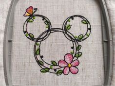 a mickey mouse head with flowers and butterflies on it's face is embroidered onto the side of a piece of fabric