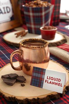 a cup of hot chocolate sitting on top of a wooden tray next to some cookies