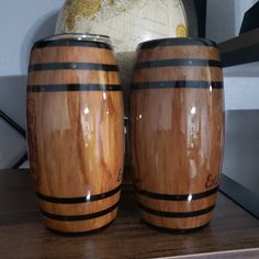 two wooden barrels sitting next to each other on top of a table with a globe in the background