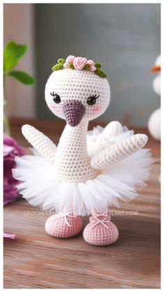 a crocheted white bird with a pink flower crown on it's head