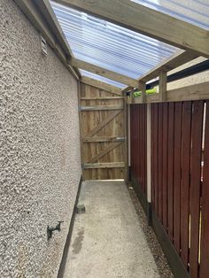 a wooden fence next to a building with a skylight on top of the roof