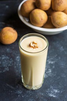 a glass filled with milk next to some fruit