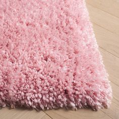 a pink rug is laying on the floor with wood floors in front of it and an area rug that has been made to look like a shaggy carpet