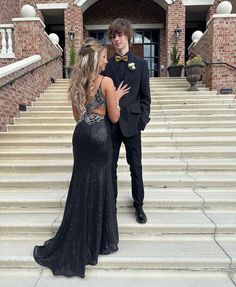 a man in a tuxedo standing next to a woman in a black dress