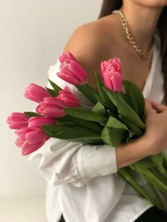 a woman holding a bouquet of pink tulips