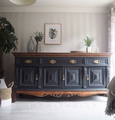 a black and gold dresser in a living room with potted plants on the top