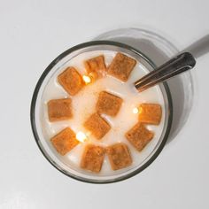 a glass filled with milk and marshmallows on top of a white table