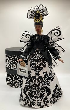 a black and white doll with a crown on her head, sitting next to a box