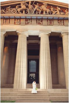 a woman in a wedding dress standing on the steps of an old building with columns