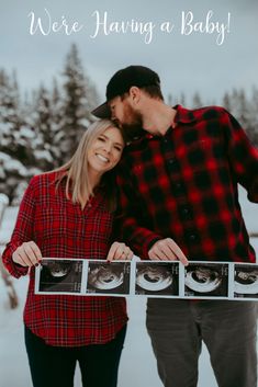 a man and woman standing next to each other in the snow holding up their baby's photo