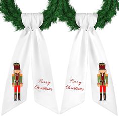 two white christmas ties with nutcrackers on them hanging from a green garland