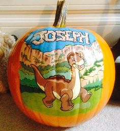 a stuffed animal next to a pumpkin with an image of a t - rex on it