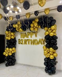 an arch made out of black and gold balloons