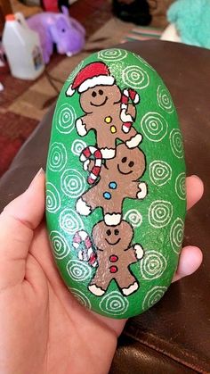 a hand holding a painted rock with gingerbreads on it