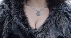 a close up of a woman wearing a fur coat with a necklace on her neck