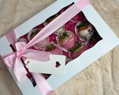 a box filled with chocolate covered strawberries and topped with a pink satin ribbon tied around the top