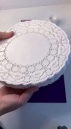 a person holding a paper doily on top of a table