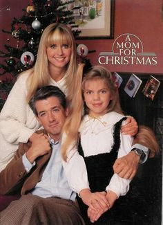 a man and woman sitting next to each other in front of a christmas tree