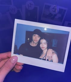 a person holding up a polaroid with an image of two people