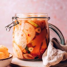 a glass jar filled with pickles and chips on top of a plate next to a bowl