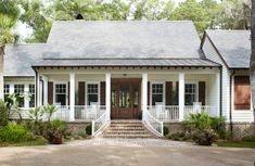 a white house with brown shutters on the front door and steps leading up to it