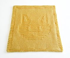 a close up of a knitted placemat on a white surface with a cat design