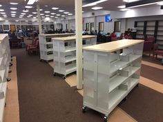 an empty library filled with lots of shelves and people sitting at desks in the background