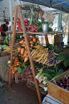 an outdoor market with vegetables and fruits on display