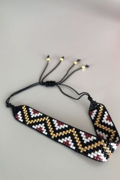 the beaded bracelet is made with black, yellow and white beads on a string