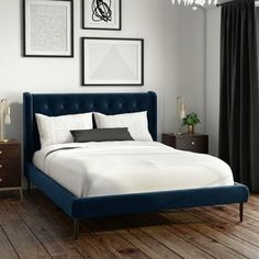 a white bed with blue headboard and foot board in a bedroom next to a window