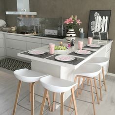 a kitchen with white counter tops and wooden stools next to an island in the middle