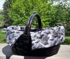 a black and white bag sitting on top of a sidewalk next to trees in the background