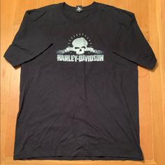 a black harley davidson t - shirt sitting on top of a wooden floor