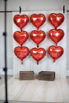 red heart balloons hanging on a wall in front of a wooden box and some wood blocks