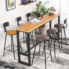 a table with four stools and a potted plant on it in front of a white brick wall