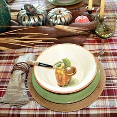 a table topped with plates and candles on top of a checkered cloth covered table