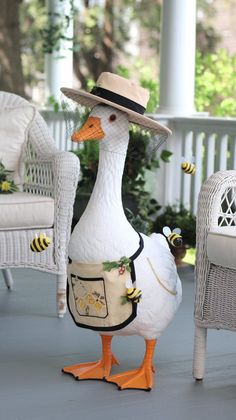 a duck wearing a hat and apron with bees on it's chest standing in front of a chair