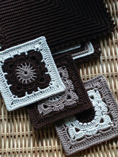 four crocheted coasters sitting on top of a wicker placematt