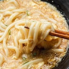 chopsticks are being used to stir noodles in a bowl