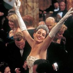 a woman wearing a tiara and holding her arms up in the air while surrounded by people