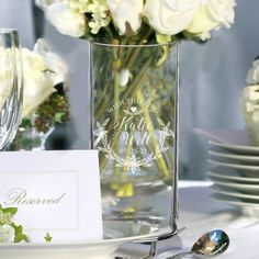 there is a vase with white flowers in it and a place card on the table