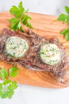 a piece of steak with parsley on top and some sauce in the middle sitting on a cutting board