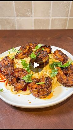 a white plate topped with pasta covered in sauce and shrimp on top of a wooden table