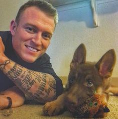 a man is laying on the floor with his arm tattooed and holding a stuffed animal