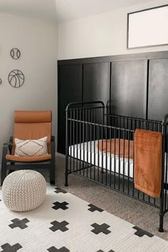 a baby's room with black crib, white rug and orange chair in the corner